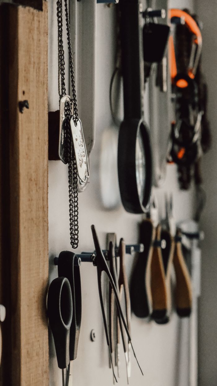 Industrial-style workspace displaying various hanging tools against a wall.
