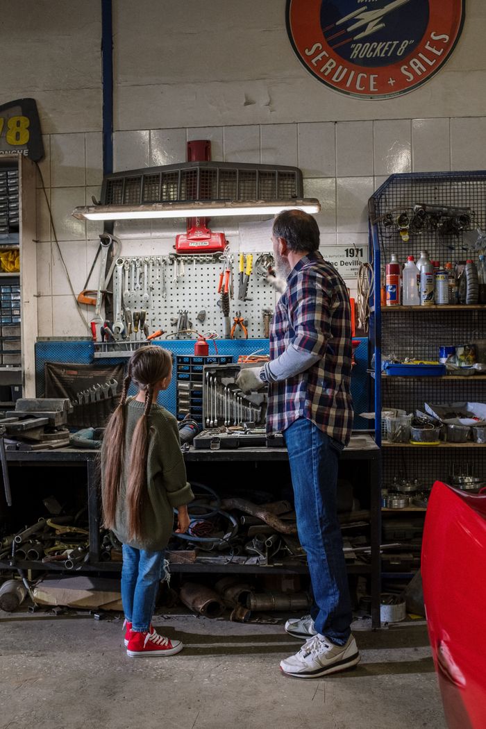 Father and daughter explore tools together in a cozy workshop setting.