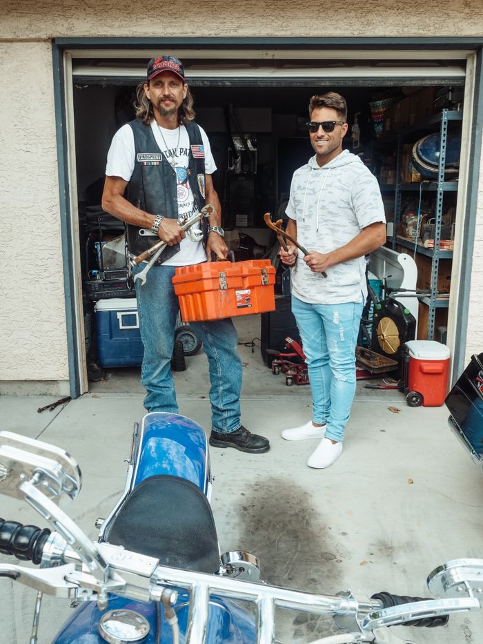 Father and son working on motorcycle repair in garage, showcasing family bonding and teamwork.